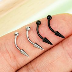 three different types of nose piercings on someone's finger with black balls and silver spikes