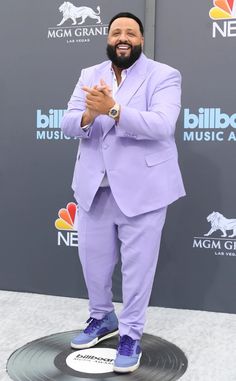 a man in a purple suit and blue shoes standing on a black platform at the billboard music awards