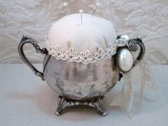 an antique teapot with buttons and lace on the handle is sitting on a table