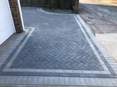 a brick driveway in front of a garage with an open door on the other side