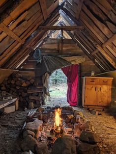 an open fire pit in the middle of a room with wooden walls and beams on it