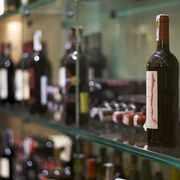 a bottle of wine sitting on top of a glass shelf next to bottles of wine