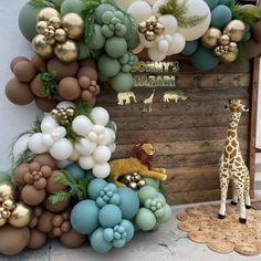 a giraffe standing in front of a wall with balloons and decorations on it