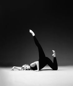 a woman in black leotard doing a handstand on the floor with her legs spread out