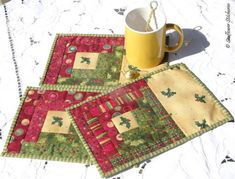 three quilted placemats on a table with a coffee cup in the middle