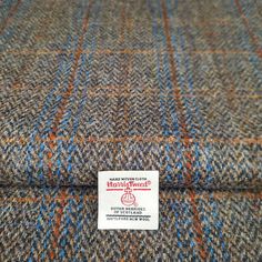 a label on the back of a tweed fabric with blue, orange and brown colors