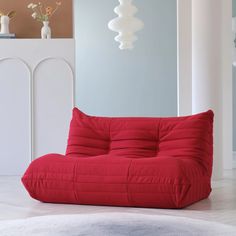 a red bean bag chair sitting on top of a white rug in a living room