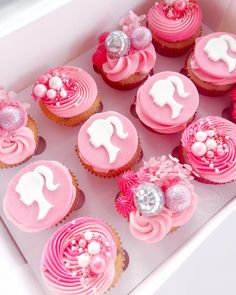 cupcakes decorated with pink frosting and white icing are in a box