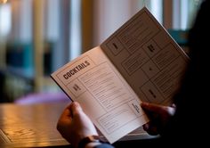 a person sitting at a table with a menu in front of them, reading the menu