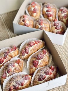 several pastries in boxes with powdered sugar and strawberries on the top one