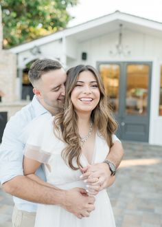 a man and woman hugging each other in front of a building