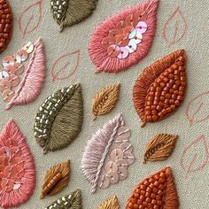 several different types of embroidered flowers on a piece of fabric with pink, orange and brown colors