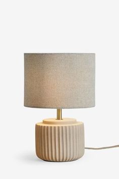 a table lamp with a beige shade on it and a cord plugged into the base