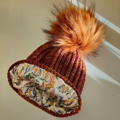 a knitted hat with an orange fur pom - pom attached to it