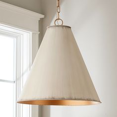 a lamp hanging from the ceiling in a room with white walls and windows behind it