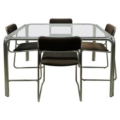 a glass dining table with four chairs around it and one chair on the other side