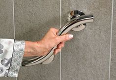 a person's hand holding onto a shower faucet in a tiled bathroom