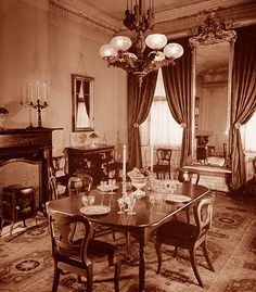 an old black and white photo of a formal dining room set up for two people