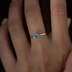 a woman's hand with a ring on it and a blue stone in the middle