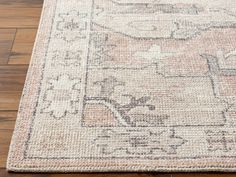 a beige and brown rug with an ornate design on the top, sitting on a wooden floor