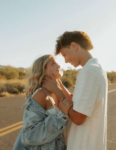 a man and woman standing next to each other in the middle of an open road