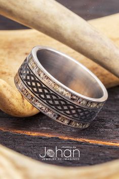 a ring with an intricate design is sitting on a piece of wood next to a baseball bat