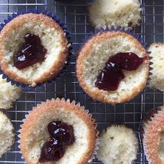 several cupcakes with jam on them sitting on a cooling rack