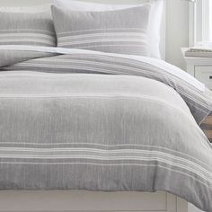 a bed with grey and white striped comforter