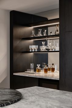 a marble counter top with glasses on it in a room that has dark wood cabinets and shelving