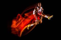 a basketball player is in the air with his foot up and motion blurry behind him