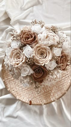 a bouquet of flowers sitting on top of a white sheet covered tablecloth with an unmade basket in the middle