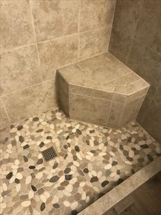 a tiled shower stall with a bench and tile flooring in the shower area is shown