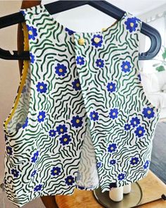 a white and blue dress with flowers on it sitting on top of a wooden table