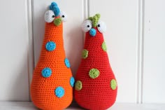 two crocheted pears sitting next to each other in front of a white wall