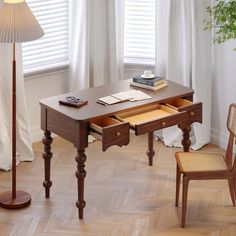 a wooden desk with two drawers and a lamp next to it on top of a hard wood floor