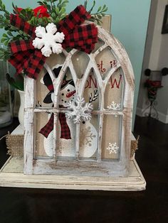 an old window is decorated with snowmen and plaid ribbon