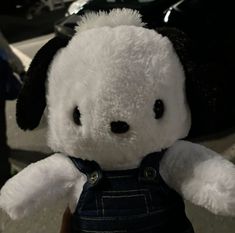 a white teddy bear wearing overalls and a black hat on top of it's head