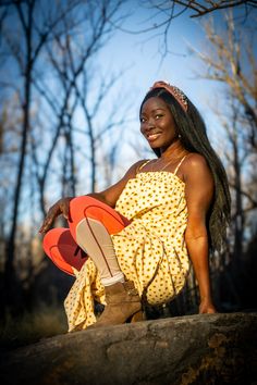 a woman sitting on top of a rock in a yellow dress