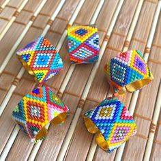 four colorful beaded bracelets sitting on top of a bamboo mat next to each other