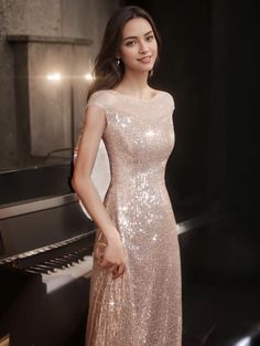 a woman standing in front of a piano wearing a pink sequined evening dress