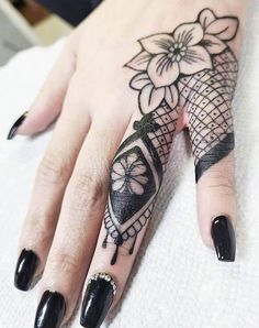 a woman's hand with black nail polish and tattoos on her left hand, holding a