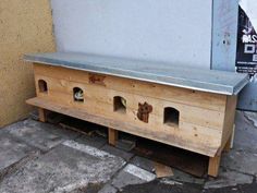 a wooden bench sitting next to a building with holes in the top and bottom part