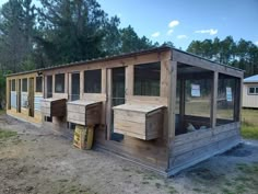 a chicken coop in the middle of a field with several windows on each side and one door open