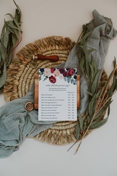 an arrangement of flowers and leaves on a table with a menu card in the middle