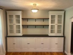 an empty room with white cabinets and wood floors