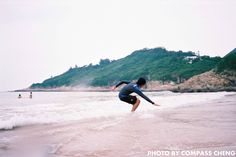 a man riding a wave on top of a surfboard in the ocean next to a mountain