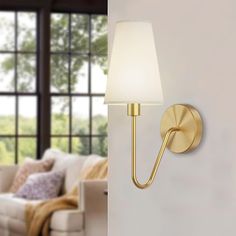 a wall light that is on the side of a wall next to a couch and window