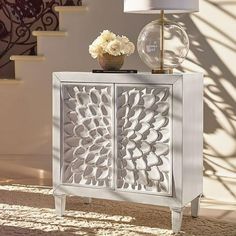 a white cabinet sitting on top of a carpeted floor next to a vase with flowers