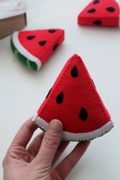 a hand holding a piece of felt with watermelon slices on it