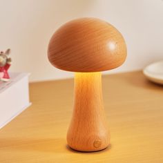 a wooden mushroom lamp on a table next to a small figurine and book